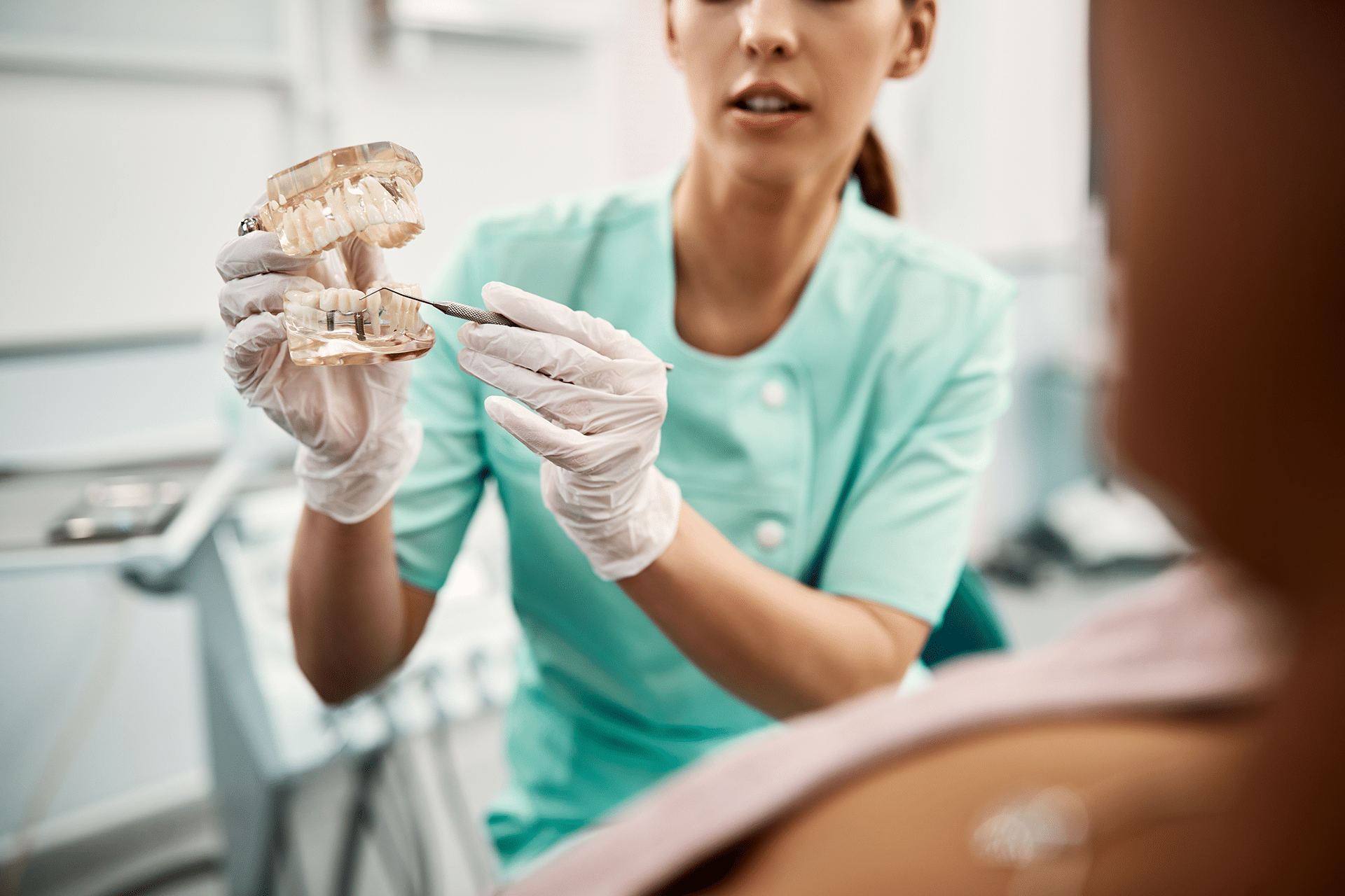 Close-up of a dentist at Aura Dental Clinic explaining dental health while pointing to a model of teeth.