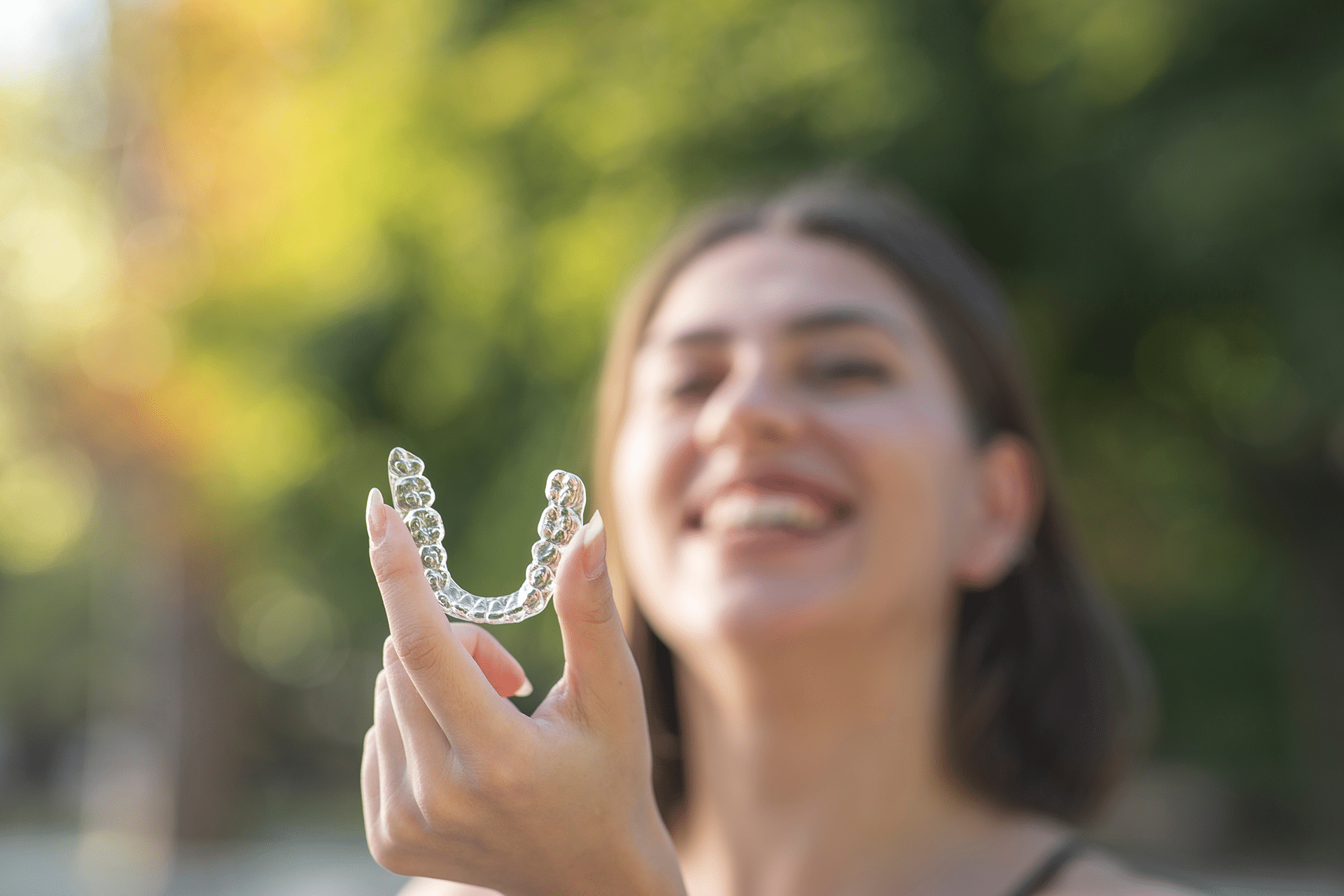 A smiling Turkish girl at Aura Dental Clinic holds a toothbrush, promoting dental hygiene and care.
