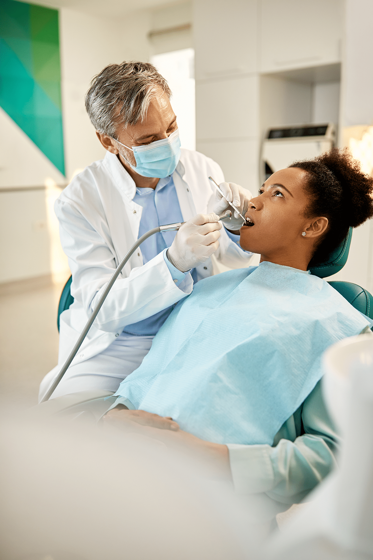 Teen receiving a dental checkup at Aura Dental Clinic, sitting in a dental chair with a dentist examining their teeth.