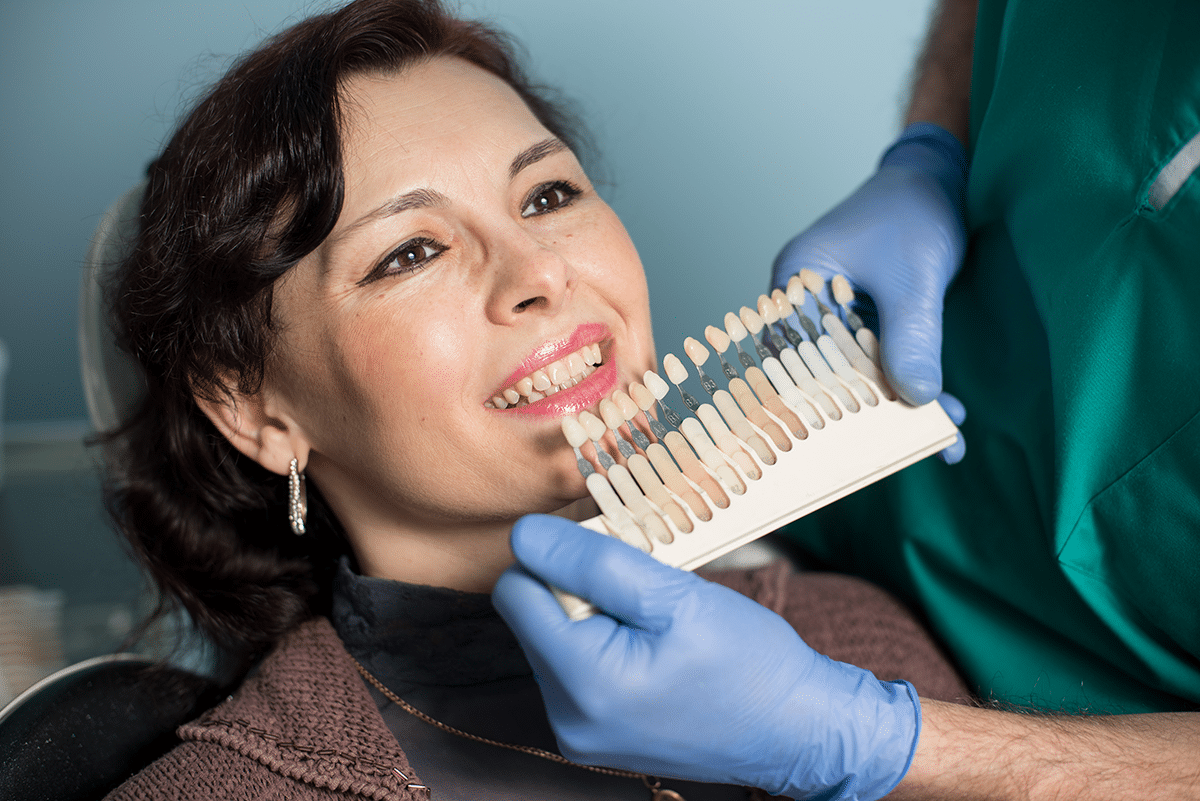 Woman at Aura Dental Clinic fitting dental veneers, smiling as she consults with a dentist in a modern clinic setting.