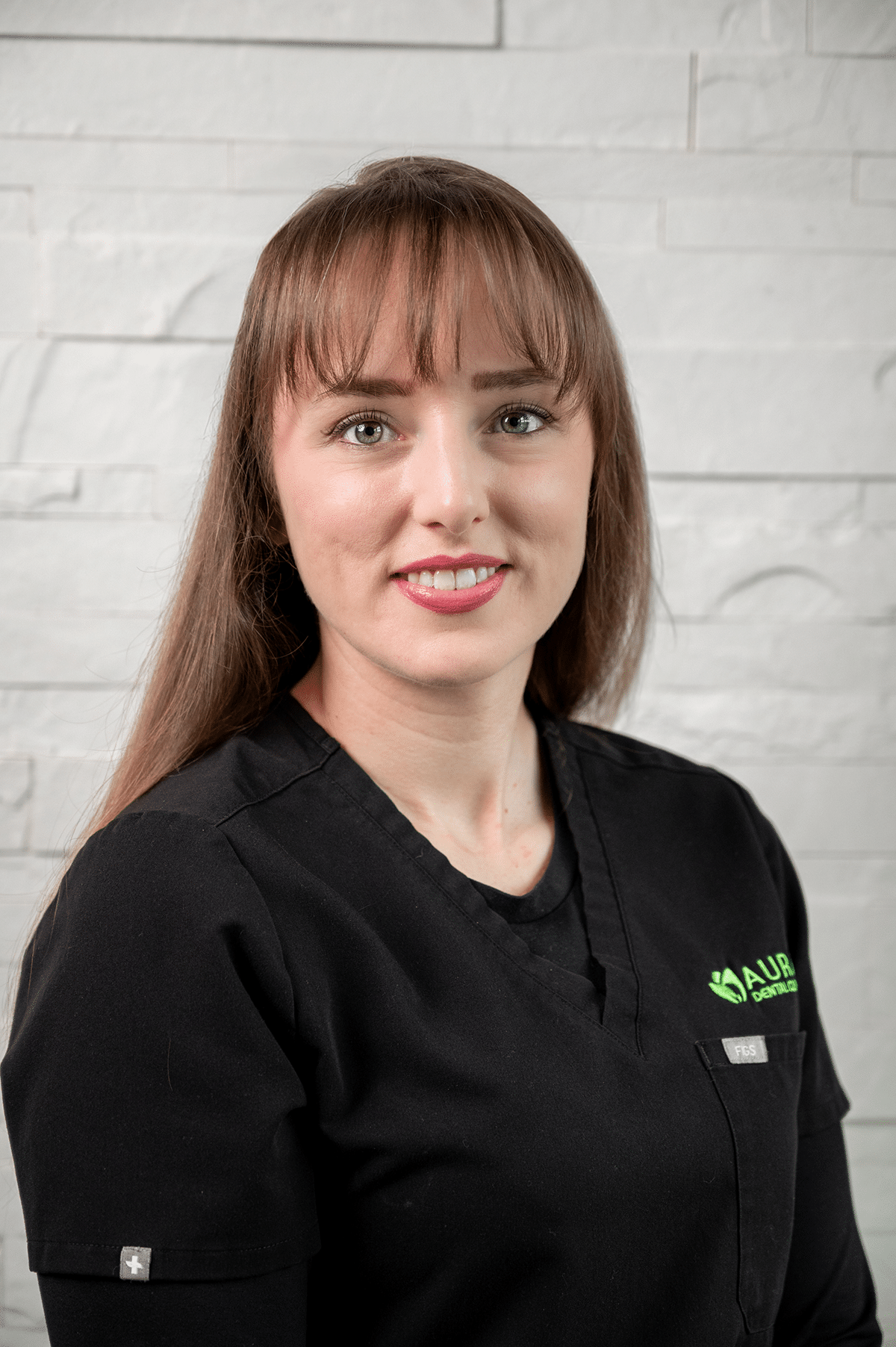 A woman wearing a black shirt and green shirt stands in front of Aura Dental Clinic, named 'Courtney'.