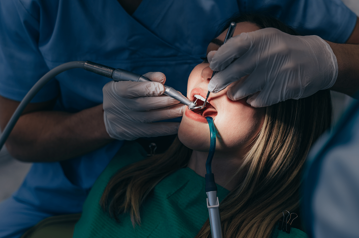A woman receiving a root canal treatment at Aura Dental Clinic, with a dentist cleaning her teeth.