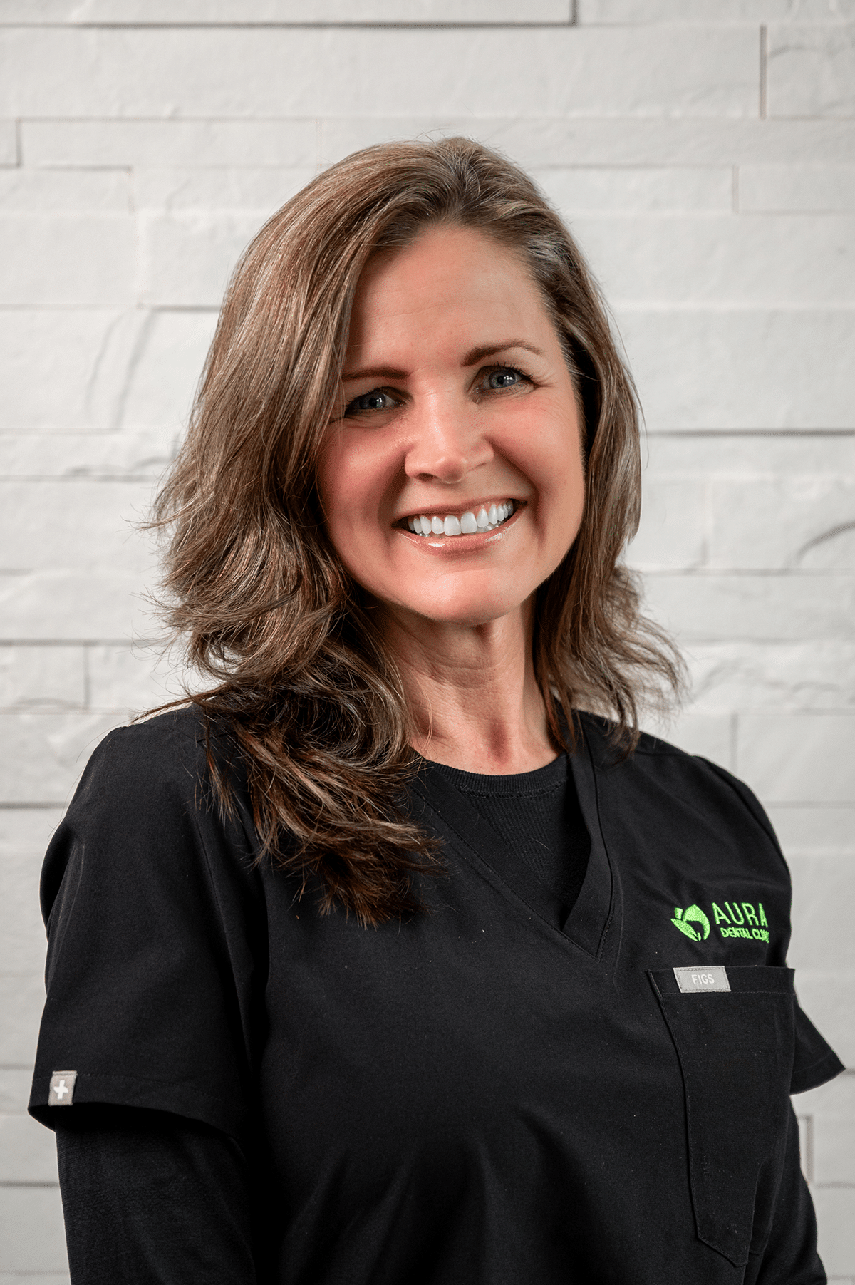 A woman wearing a black shirt and green shirt stands in front of Aura Dental Clinic, named 'Lorilee'.