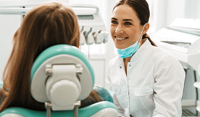 A dentist smiling at a patient in a dental office.